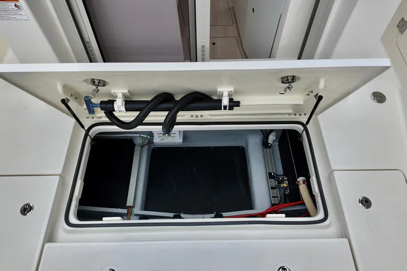 Slide: The Image of 2026 Bayliner Trophy T25 Pilothouse storage compartment with open hatch and visible wiring. - 20