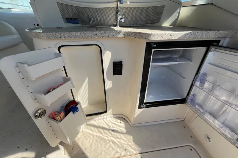 Slide: The Image of 2000 Rinker 340 Fiesta Vee boat interior with open mini fridge and storage compartments. - 16
