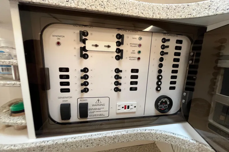 Slide: The Image of Control panel of a 2000 Rinker 340 Fiesta Vee boat, featuring generator and circuit switches. - 49