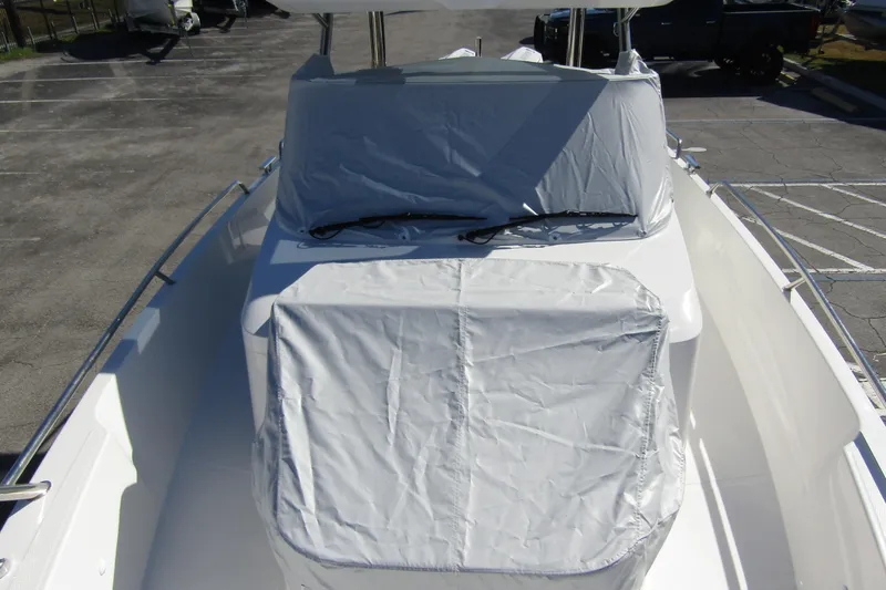 Slide: The Image of 2025 Nimbus Tender 9 boat with protective covers in a parking area. - 12