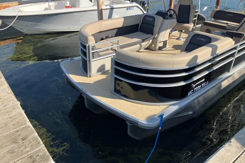 Slide: The Image of 2025 Harris Cruiser 230 pontoon boat docked on calm water. - 1