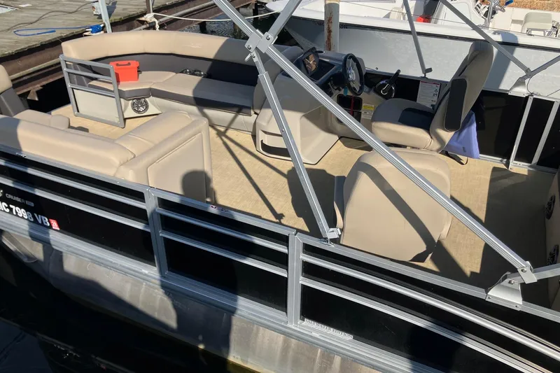 Slide: The Image of 2025 Harris Cruiser 230 pontoon boat with beige seating and modern helm. - 3