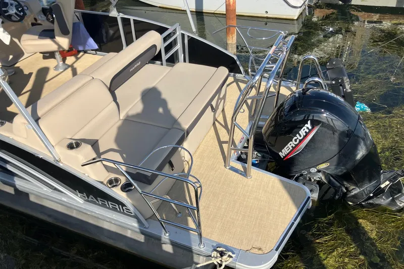 Slide: The Image of 2025 Harris Cruiser 230 pontoon boat with Mercury outboard engine, docked on water. - 4