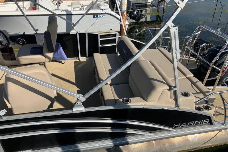 Slide: The Image of 2025 Harris Cruiser 230 pontoon boat with beige seating and sleek design. - 5