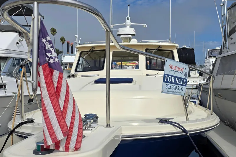 Slide: The Image of 2005 Mainship 34 Pilot Sedan Rum Runner II for sale at marina, American flag displayed. - 2