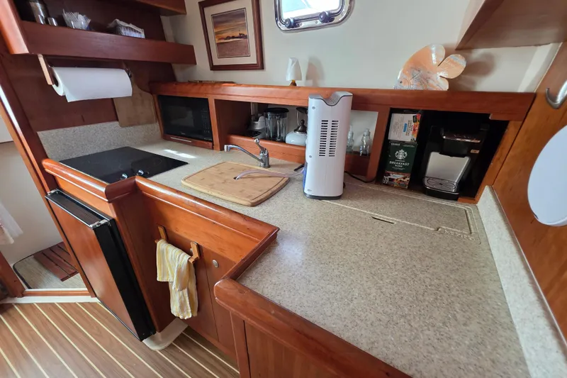 Slide: The Image of 2005 Mainship 34 Pilot Sedan Rum Runner II galley with wooden cabinetry and modern appliances. - 29