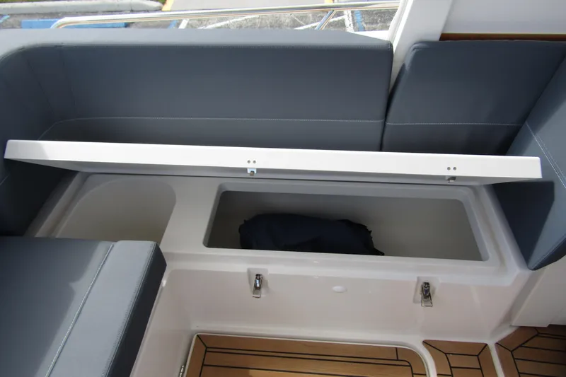 Slide: The Image of 2025 Nimbus Weekender 9 boat storage compartment with open lid and cushioned seating. - 44