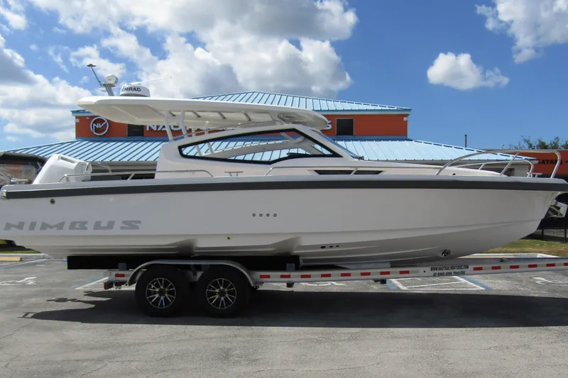 Slide: The Image of 2025 Nimbus Weekender 9 boat on trailer, parked outdoors under a cloudy sky. - 5