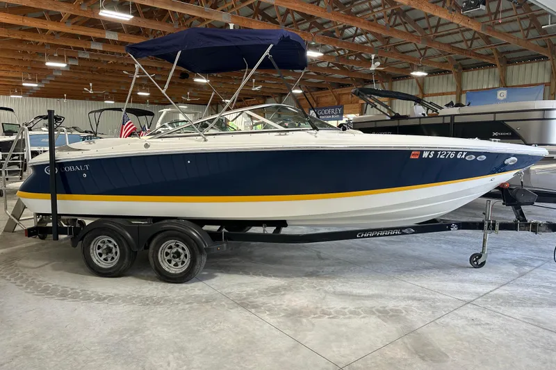 The Image of 2006 Cobalt 220 boat on trailer in indoor showroom with blue and yellow accents. - 1
