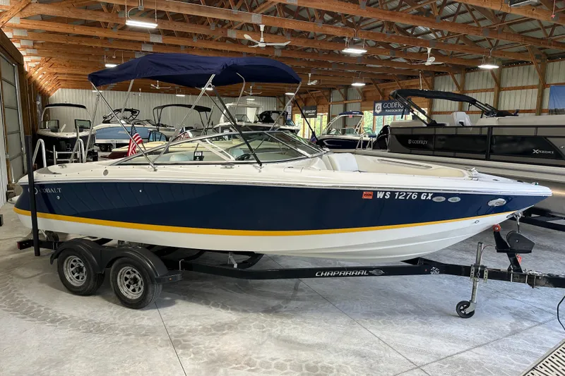 Slide: The Image of 2006 Cobalt 220 boat with blue and white design on a trailer in a storage facility. - 2