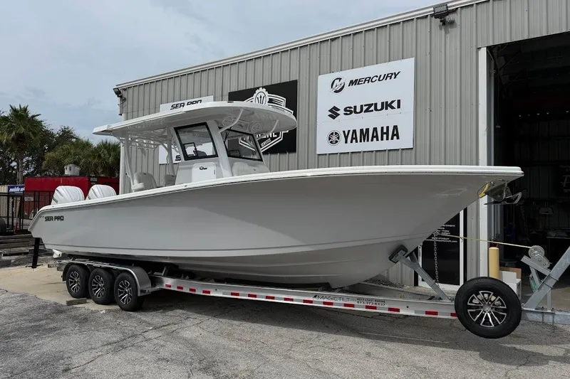 The Image of 2026 Sea Pro 322 Offshore boat on trailer outside dealership with Mercury, Suzuki, Yamaha signs. - 1