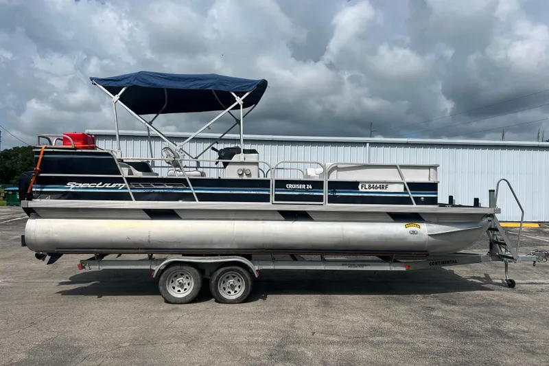 The Image of 1991 Spectrum 24 Cruise pontoon boat on trailer, blue canopy, parked outdoors. - 1