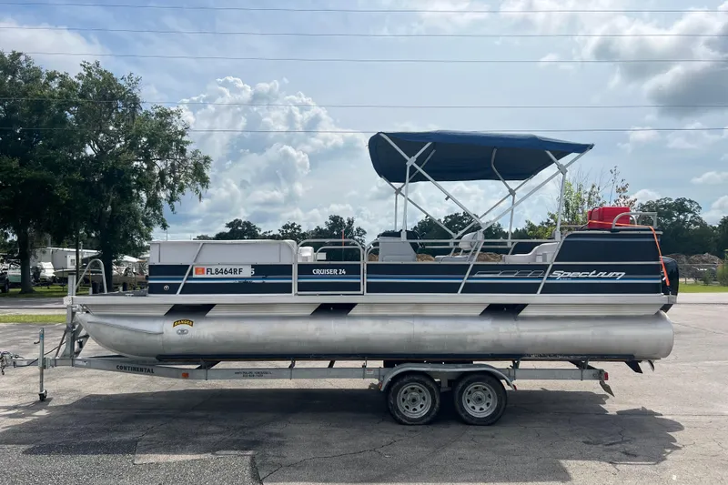 Slide: The Image of 1991 Spectrum 24 Cruise pontoon boat on trailer, parked outdoors under cloudy sky. - 4