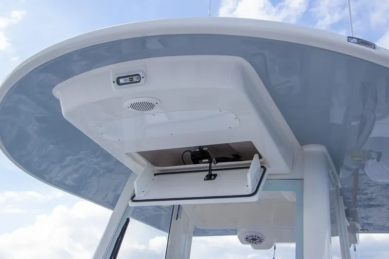 Slide: The Image of 2026 Regulator 28 boat with open storage compartment under T-top against blue sky. - 46