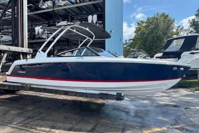 The Image of 2026 Cobalt CS23 boat with sleek design, blue hull, and red stripe, displayed outdoors. - 1