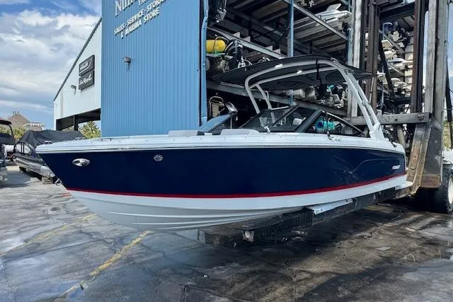 Slide: The Image of 2026 Cobalt CS23 boat in storage facility, blue and white design. - 7