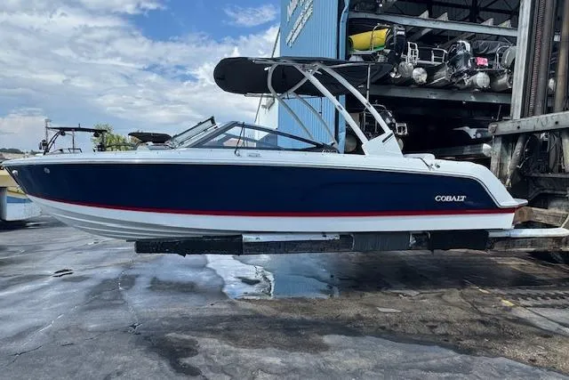 Slide: The Image of 2026 Cobalt CS23 boat with blue hull and red stripe, docked outdoors. - 8