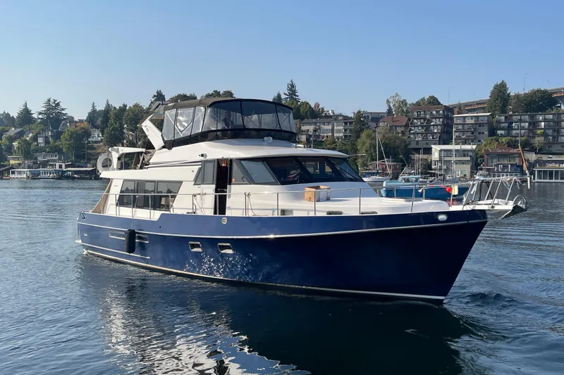 Slide: The Image of 1995 Ocean Alexander 486 yacht cruising on a calm waterway, surrounded by scenic waterfront homes. - 2