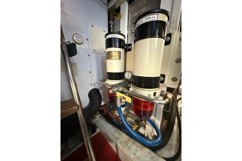 Slide: The Image of Engine room of 1995 Ocean Alexander 486 yacht, featuring dual fuel filters and piping. - 54