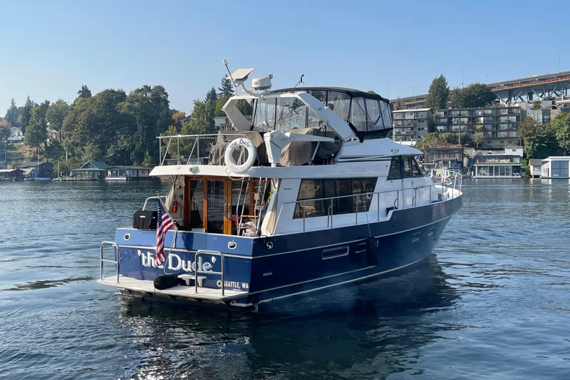 Slide: The Image of 1995 Ocean Alexander 486 yacht on water, with American flag, near shoreline and buildings. - 7