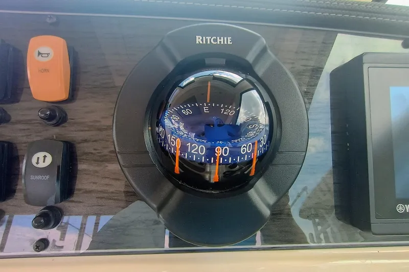 Slide: The Image of Compass and controls on 2021 Grady-White Freedom 375 boat dashboard. - 27