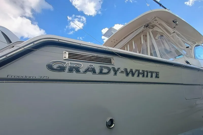 Slide: The Image of 2021 Grady-White Freedom 375 boat exterior with logo under blue sky. - 34