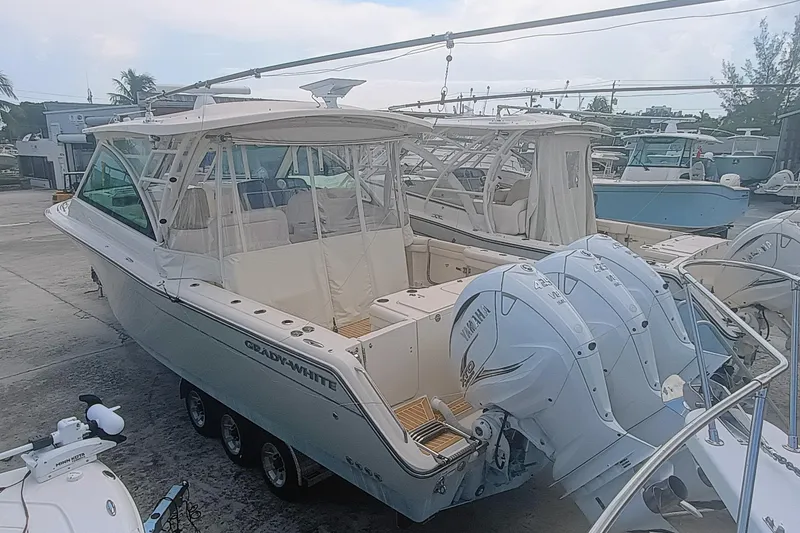 Slide: The Image of 2021 Grady-White Freedom 375 boat with triple Yamaha engines in a marina setting. - 4