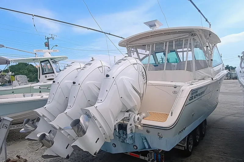 Slide: The Image of 2021 Grady-White Freedom 375 boat with triple outboard engines, docked under blue sky. - 5