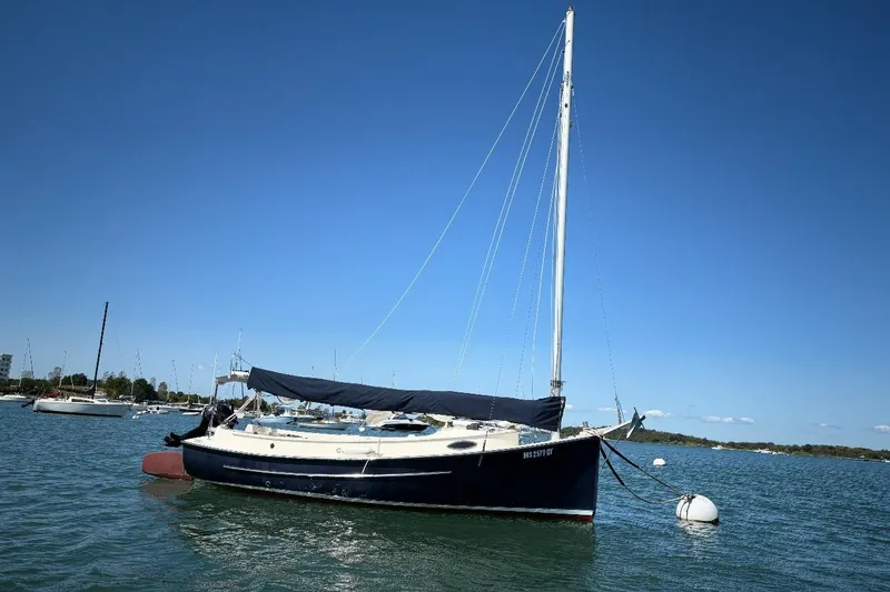 Slide: The Image of 2014 Com-Pac Horizon Day Cat sailboat anchored on calm water under clear blue sky. - 4