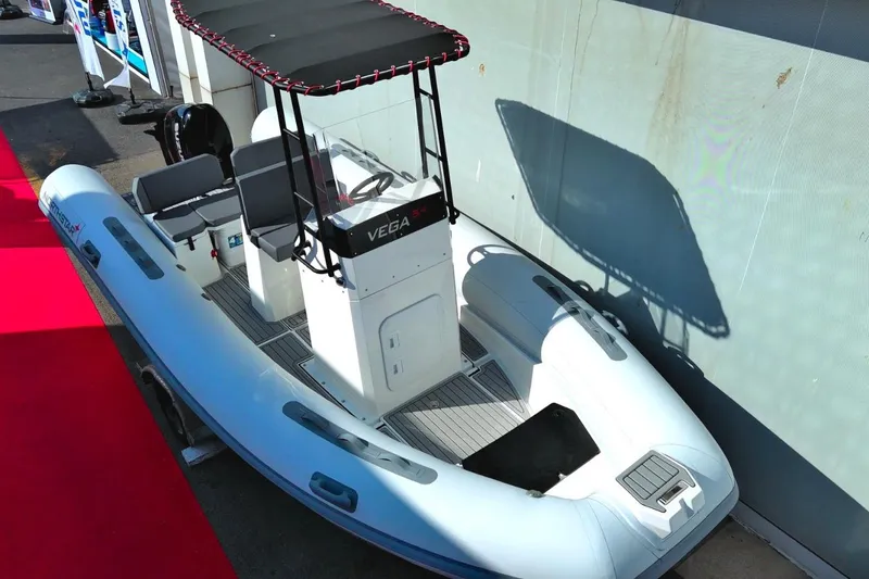 Slide: The Image of 2026 Northstar VEGA 5.4 inflatable boat with canopy, displayed on a red carpet. - 4