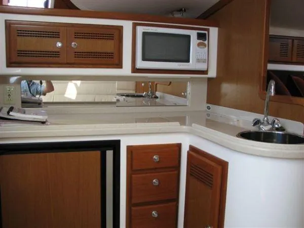 Slide: The Image of 2001 Cabo 35 Express yacht kitchen with microwave, sink, and wooden cabinetry. - 19