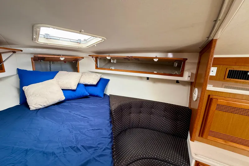 Slide: The Image of 2001 Cabo 35 Express cabin interior with blue bedding and wooden storage cabinets. - 20