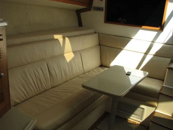 Slide: The Image of 2001 Cabo 35 Express interior with beige leather seating and table, sunlight streaming in. - 22
