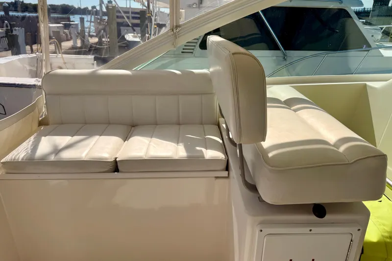 Slide: The Image of 2001 Cabo 35 Express boat interior with white cushioned seating in sunlight. - 35