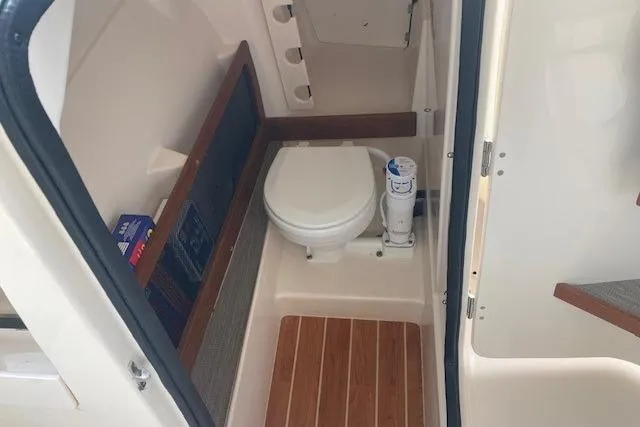 Slide: The Image of 2022 Grady-White Freedom 275 boat interior with compact marine toilet and wooden flooring. - 10