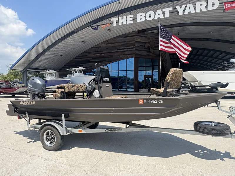 Slide: The Image of 2023 Alweld 16x52 Marsh boat with Yamaha 70 outboard motor, parked outdoors. - 2