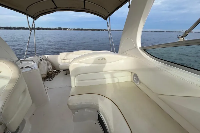 Slide: The Image of 2003 Sea Ray 280 Sundancer interior with white seating, open cabin door, and ocean view. - 28