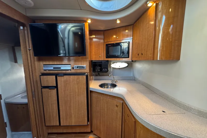 Slide: The Image of 2002 Regal Commodore 3860 yacht interior with kitchenette, TV, and wooden cabinetry. - 29