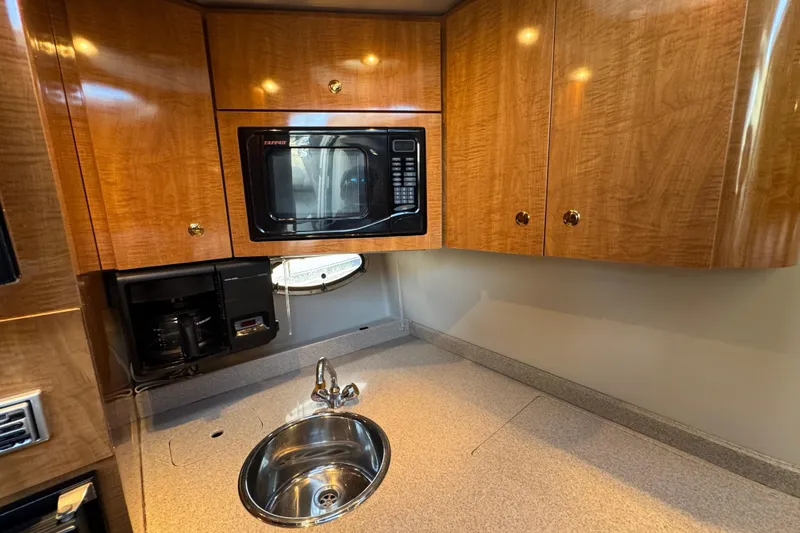 Slide: The Image of 2002 Regal Commodore 3860 yacht kitchen with microwave, sink, and wooden cabinets. - 34