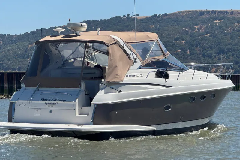 Slide: The Image of 2002 Regal Commodore 3860 yacht cruising on a sunny day, featuring tan canopy and sleek design. - 4