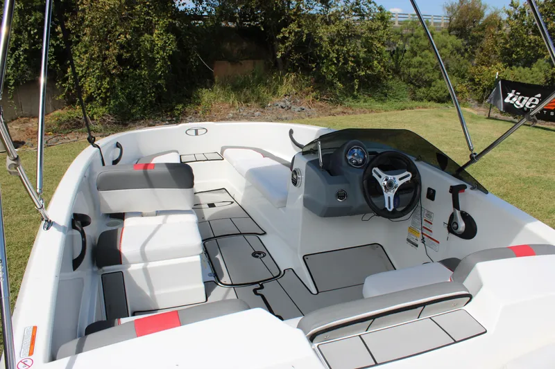 Slide: The Image of 2021 Tahoe T16 boat interior with modern steering and seating, set outdoors. - 10