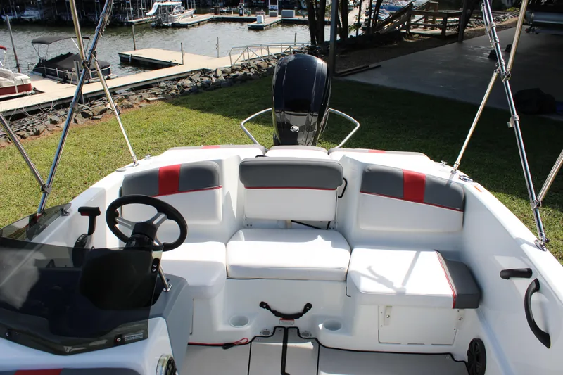 Slide: The Image of 2021 Tahoe T16 boat interior with seating, steering wheel, and motor, docked by a lakeside. - 14