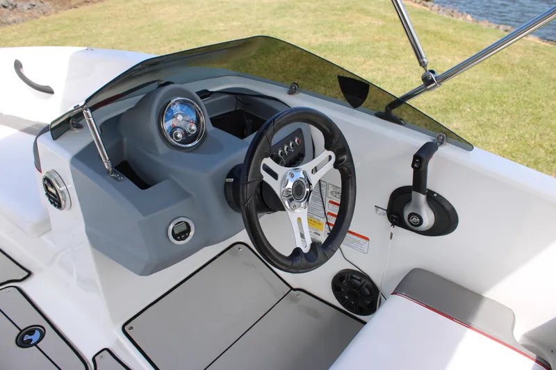 Slide: The Image of 2021 Tahoe T16 boat dashboard with steering wheel and controls, near water and grass. - 15