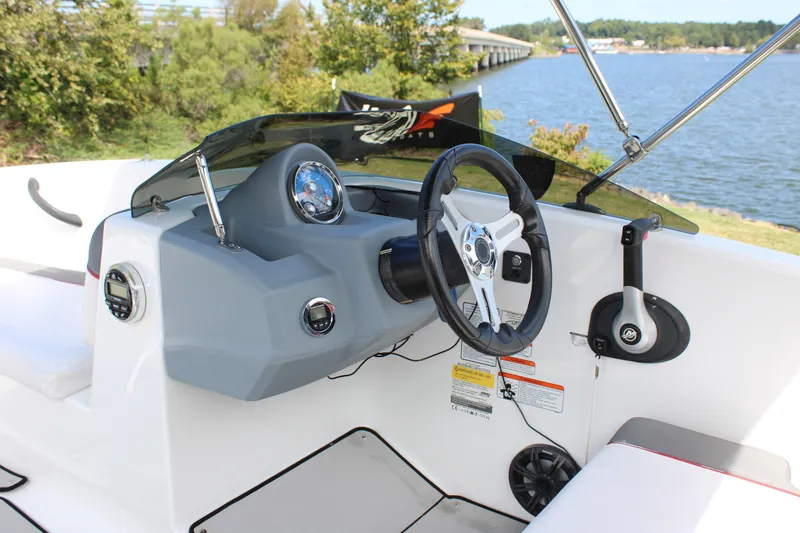 Slide: The Image of 2021 Tahoe T16 boat dashboard with steering wheel, controls, and lake view. - 16