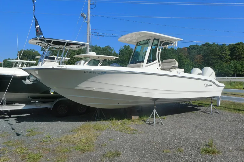 The Image of 2023 Boston Whaler 280 Dauntless boat on display, elevated on stands, with clear blue sky. - 0
