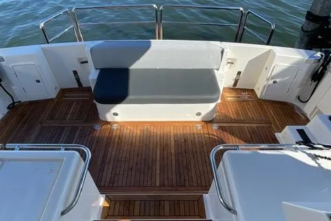 Slide: The Image of 2025 Riviera 585 SUV yacht deck with wooden flooring and cushioned seating. - 18