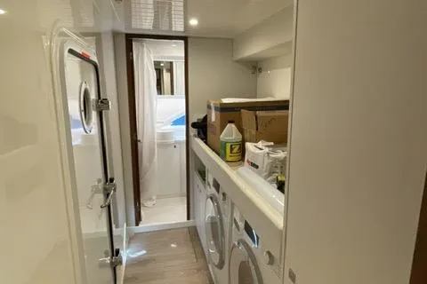 Slide: The Image of Laundry area inside 2025 Riviera 585 SUV yacht, featuring modern appliances and storage. - 31
