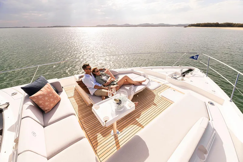 Slide: The Image of Manufacturer Provided Image: Couple relaxing on 2025 Riviera 585 SUV yacht deck, enjoying serene ocean view. - 45