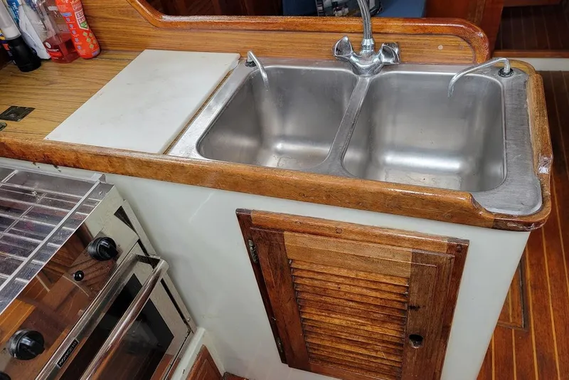 Slide: The Image of 1976 Down East Yachts Cutter kitchen with double sink and wooden cabinetry. - 13