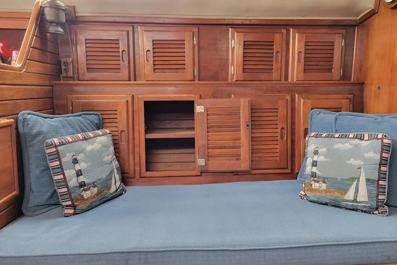 Slide: The Image of 1976 Down East Yachts Cutter interior with wooden cabinets and nautical-themed cushions. - 15